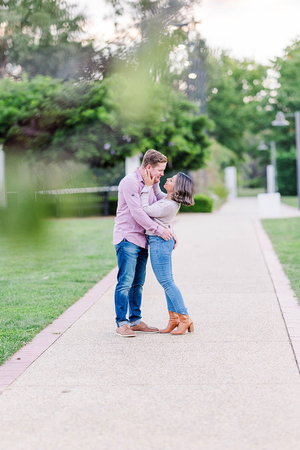 red haired man stares lovingly at a sri lankan woman both wearing blue jeans in the middle of a garden path